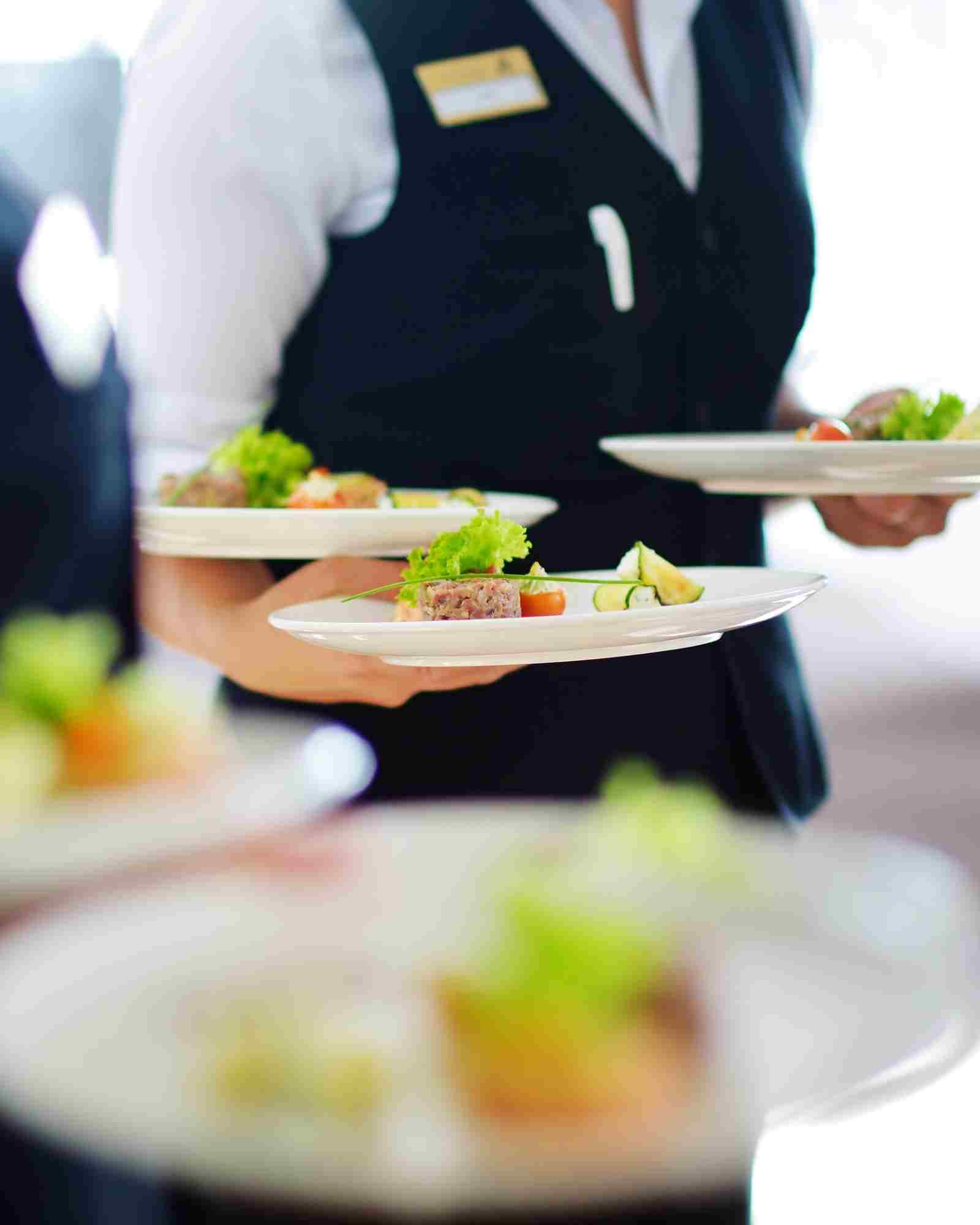 Serveur français portant des plats en salle de restaurant